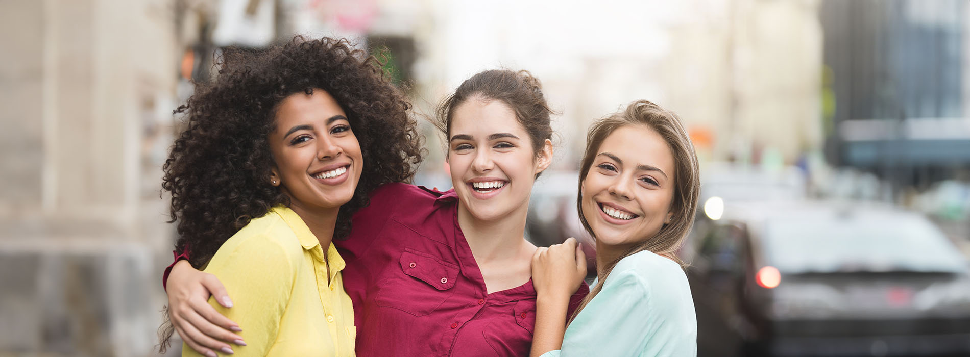 The image shows four individuals posing together with smiles, standing outdoors on a city street at night.