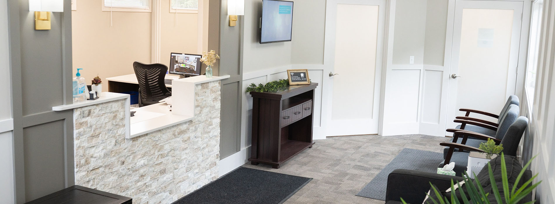 A panoramic view of an office lobby with a reception desk, chairs, and a large window.
