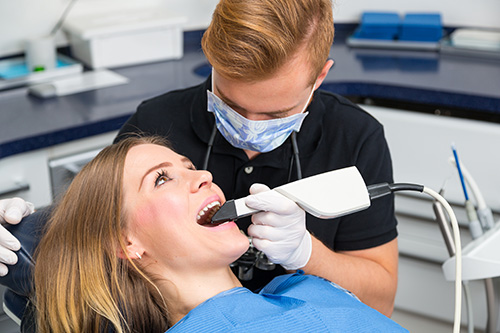 A woman receiving dental treatment from a dentist using a drill, with two different perspectives captured in the composite image.