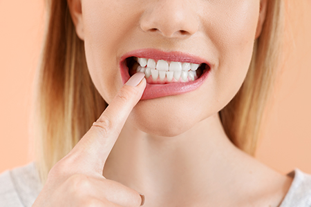 A close-up photograph of a person with their finger on their teeth, appearing to be in the process of brushing them.